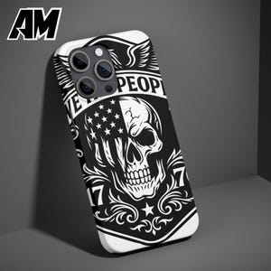 Puede incluir: Funda de tel&eacute;fono en blanco y negro con un dise&ntilde;o de calavera y un motivo de bandera estadounidense. La funda tiene el texto "WE THE PEOPLE" y el n&uacute;mero "17". La funda est&aacute; hecha de un material duro y protector.