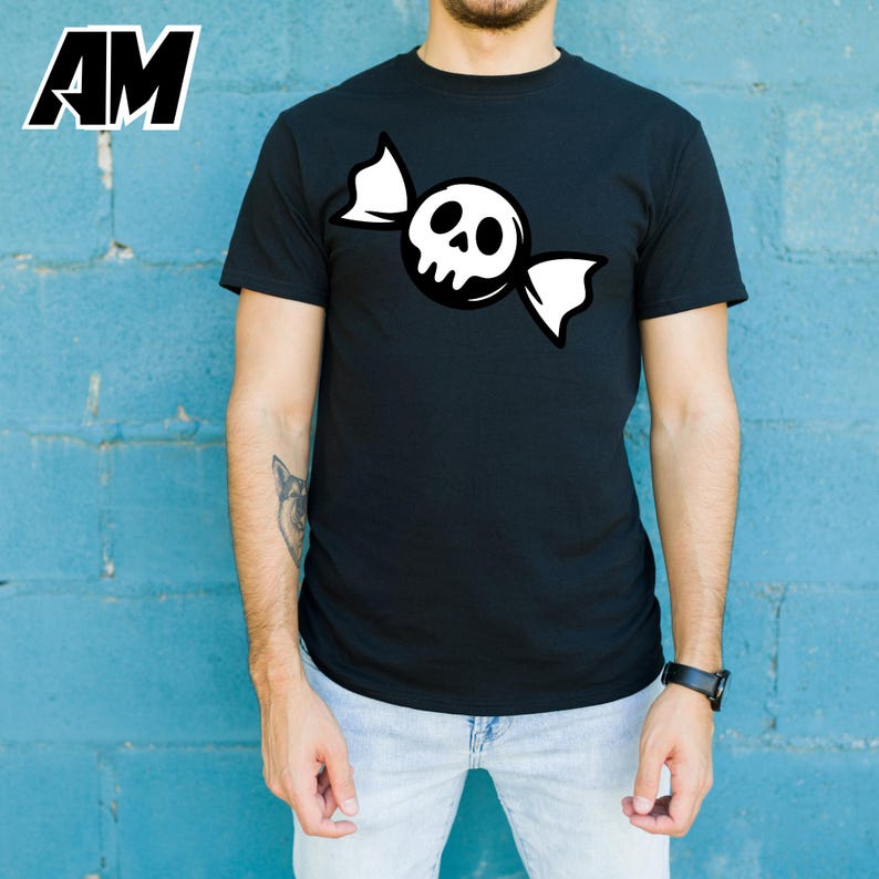 May include: Black t-shirt featuring a white skull candy graphic. The design shows a skull with a candy wrapper. The shirt is a crew neck style. The letters "AM" are in the upper left corner.
