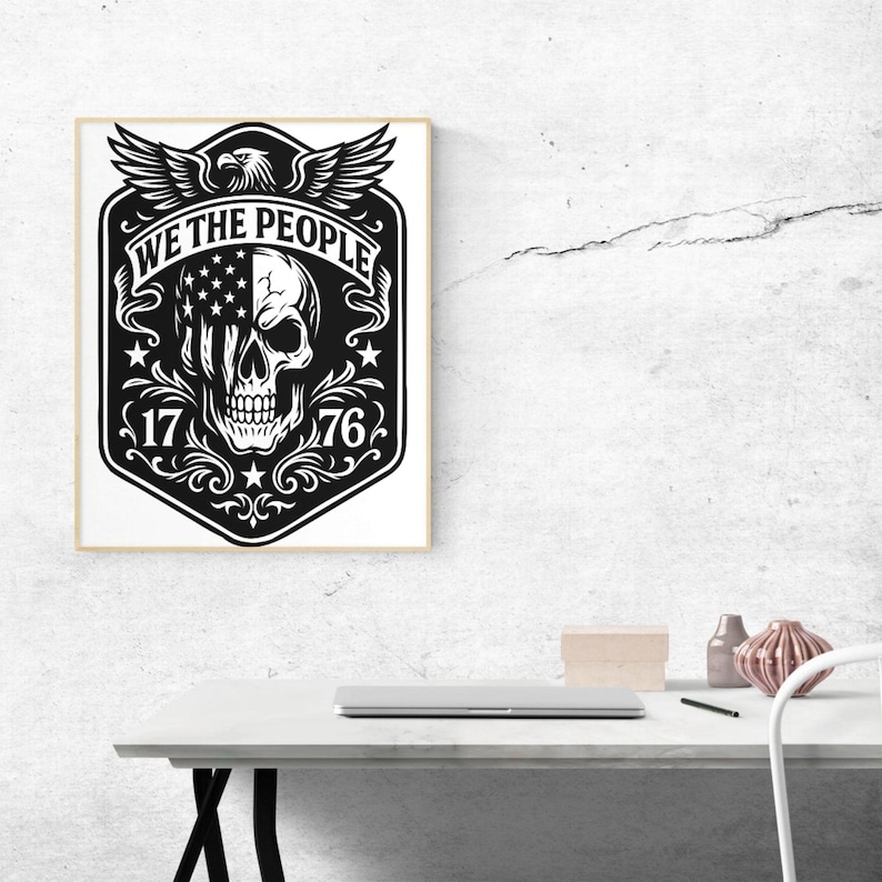Puede incluir: Impresi&oacute;n art&iacute;stica enmarcada en blanco y negro con una calavera con el dise&ntilde;o de la bandera estadounidense en un lado. Las palabras "WE THE PEOPLE" est&aacute;n sobre la calavera, con los n&uacute;meros "1776" debajo. Un &aacute;guila con las alas extendidas est&aacute; en la parte superior.