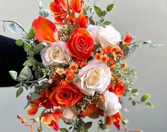 Könnte beinhalten: Ein Brautstrauß mit weißen Rosen, orangefarbenen Rosen, orangefarbenen Calla-Lilien und orangefarbenen Orchideen. Der Strauß ist mit kleinen orangefarbenen Blüten und grünem Laub verziert.