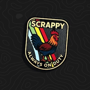 May include: A rectangular embroidered patch with rounded corners featuring a rooster with red, orange, and blue feathers. Behind the rooster are diagonal rainbow stripes. The text SCRAPPY is at the top and ALWAYS ON DUTY is at the bottom.