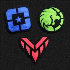 May include: Three embroidered patches on a dark background. One is a blue square with a central star, one is a circular lime green lion head emblem, and one is a red V-shaped geometric design with black outlines and internal segmented details.