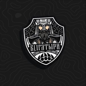 May include: A shield-shaped embroidered patch featuring a black and white graphic of a bearded warrior in a horned helmet. The warrior holds two axes, and the text "БѴГАТЫРИ" is displayed across the center above a bear paw print icon.