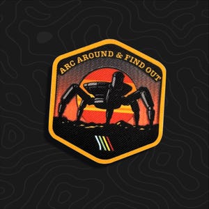 May include: A hexagonal embroidered patch with a yellow border featuring a black silhouette of a multi-legged robot against a red and orange sunset. The text ARC AROUND & FIND OUT is arched at the top, with three small diagonal stripes below.