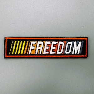 May include: A black, orange, yellow, and white embroidered patch with the word "FREEDOM" in white letters.
