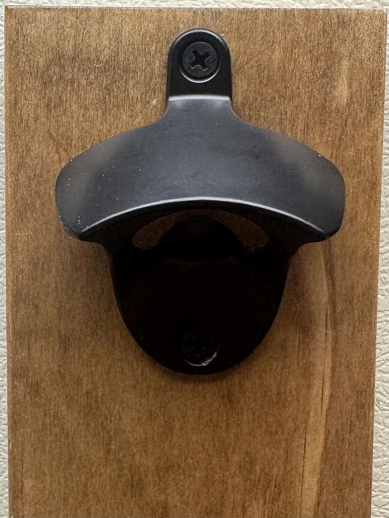 This will be the bottle opener that comes with product. The one with”Open Here” is no longer available.