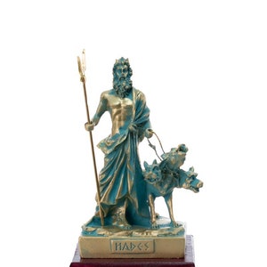 May include: A bronze statue of Hades, the Greek god of the underworld, holding a trident and accompanied by a three-headed dog. The statue is on a wooden base with the word "Hades" inscribed in Greek.