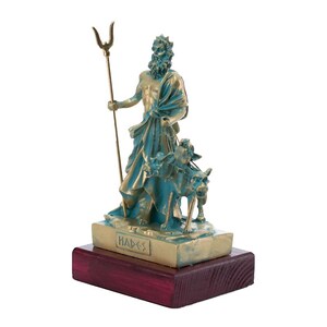 May include: A bronze statue of Hades, the Greek god of the underworld, holding a trident and accompanied by a three-headed dog. The statue is on a wooden base with the word "Hades" inscribed on it.