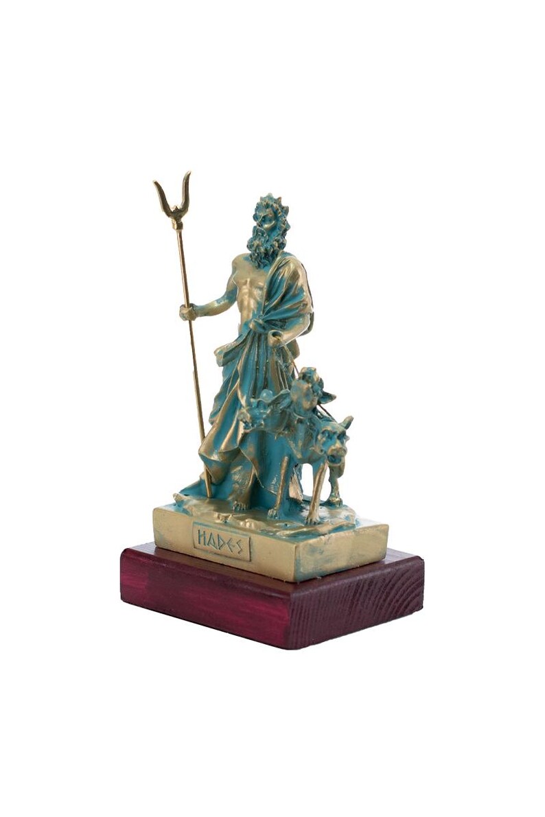 May include: A bronze statue of Hades, the Greek god of the underworld, holding a trident and accompanied by a three-headed dog. The statue is on a wooden base with the word "Hades" inscribed on it.