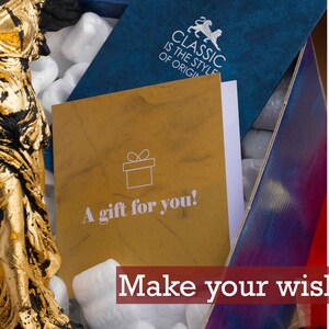 May include: A gold-colored statue of a woman in a flowing robe is in a box with packing peanuts. A card with the text "A gift for you!" is on top of the packing peanuts. The box is blue with the text "CLASSIC IS THE STYLE OF ORIGIN" on the top. The text "Make your wishes!" is at the bottom of the image.