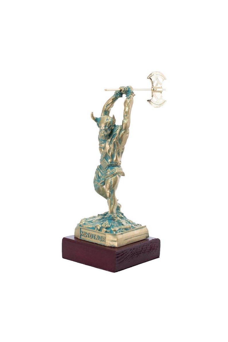 May include: A bronze statue of a minotaur holding an axe, standing on a green base with the word "Minotaur" inscribed on it. The statue is on a wooden base.