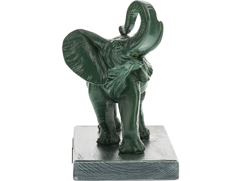 May include: Green ceramic elephant figurine with its trunk raised in the air. The elephant is standing on a square base.