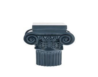 May include: A dark gray, decorative, sculpted column capital with a square top and intricate scrollwork.