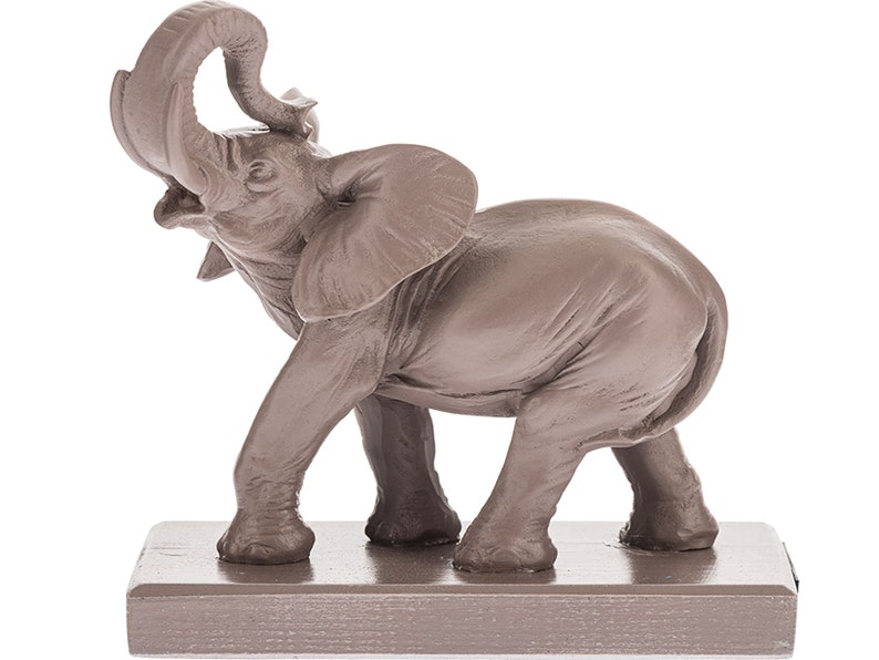 May include: A brown ceramic elephant figurine with its trunk raised in the air. The elephant is standing on a small, rectangular base.