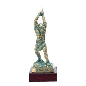 May include: A bronze sculpture of the Minotaur, a mythical creature with the head of a bull and the body of a man. The sculpture is on a wooden base with the word "Minotaur" inscribed on it.