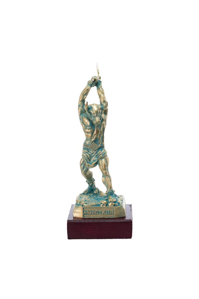 May include: A bronze sculpture of the Minotaur, a mythical creature with the head of a bull and the body of a man. The sculpture is on a wooden base with the word "Minotaur" inscribed on it.