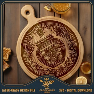 Puede incluir: Una tabla de cortar redonda de madera con un diseño grabado con láser de un tarro de miel rodeado de abejas y flores. El diseño es de color marrón oscuro y la tabla es de color marrón claro. El texto "Clockwork Bird" es visible en la parte inferior central de la imagen.