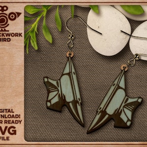 Könnte beinhalten: Ein Paar lasergeschnittene Holzohrringe in Form eines Ambosses. Die Ohrringe sind in einem hellblauen und braunen Farbschema lackiert. Die Ohrringe hängen an goldfarbenen Haken.