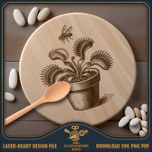 May include: A round light-coloured wooden board featuring a dark brown laser-engraved illustration of a Venus flytrap in a pot with a flying insect above it. A light-coloured wooden spoon rests on the board, surrounded by several smooth white stones.