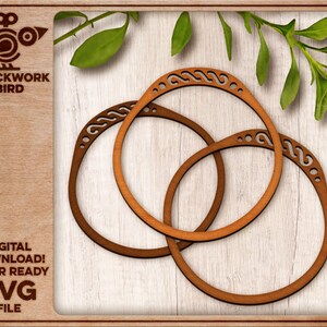 May include: Three interlocking wooden rings with intricate designs. The rings are brown and have a natural wood finish. The rings are on a light wood background.