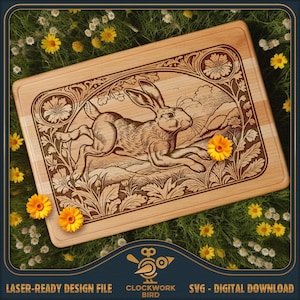 May include: A rectangular light-colored wooden cutting board featuring a laser-engraved illustration of a running rabbit surrounded by floral motifs and foliage. The design includes a decorative border with flowers in the corners and landscape details.