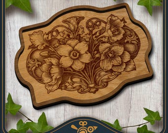May include: A light brown wooden plaque with a laser-engraved floral design featuring daffodils and swirling vine patterns. The plaque has a scalloped, irregular shape with a dark brown border, showcasing natural wood grain textures throughout.