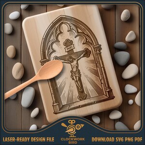 May include: A light-colored wooden cutting board featuring a laser-engraved illustration of a crucifix within a gothic archway, with the text INRI visible on the cross. A plain wooden spoon rests diagonally across the board surface.