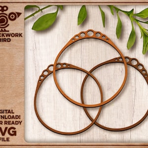 May include: Three interlocking wooden rings with a decorative, scalloped edge. The rings are arranged in a triangular pattern on a light brown wooden background.