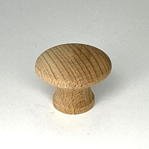 May include: A wooden mushroom-shaped cabinet knob. The knob has a rounded top with visible wood grain and a short, cylindrical base. The wood is a light brown color.