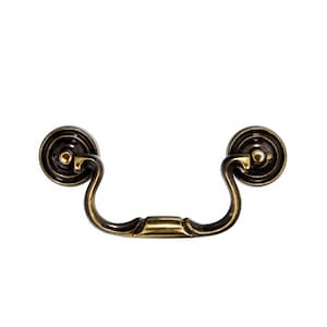 May include: A vintage-style, ornate, brass drawer pull with a curved handle and two round, decorative knobs.