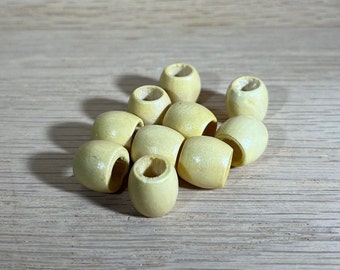 May include: A group of ten wooden beads in a pale yellow color. The beads are oval shaped with a hole through the center.