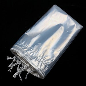 May include: Clear plastic bag with a drawstring closure. The bag is folded and the drawstring is tied.