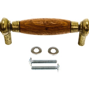 May include: A cabinet pull with a wooden center and brass-colored metal ends. The hardware includes two washers and two screws. The pull is designed for furniture and cabinetry.
