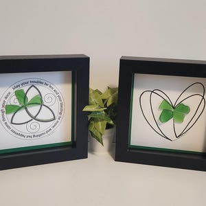 May include: Two framed pieces of art with a green four-leaf clover design. The first piece features a Celtic knot design with the text "May your troubles be less and your blessings be more and nothing but happiness come through your door." The second piece features a heart shape with a four-leaf clover inside.