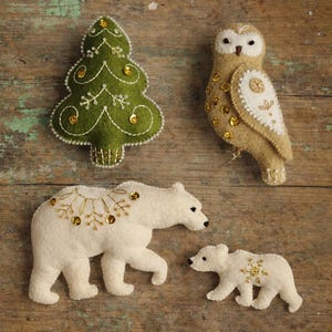 May include: A set of four felt ornaments including a green Christmas tree with gold sequins, a tan owl with white embroidery and gold sequins, a large white polar bear with gold embroidery, and a small white polar bear cub with gold embroidery.
