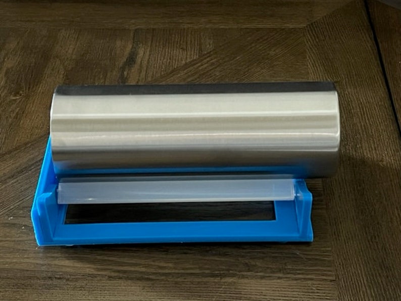 May include: A silver stainless steel tumbler in a blue and white plastic holder.