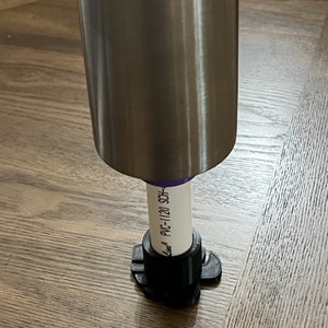May include: A close-up of a silver metal table leg with a black plastic adjustable foot. The foot has a label that reads "PVC-1120 SCH-40".