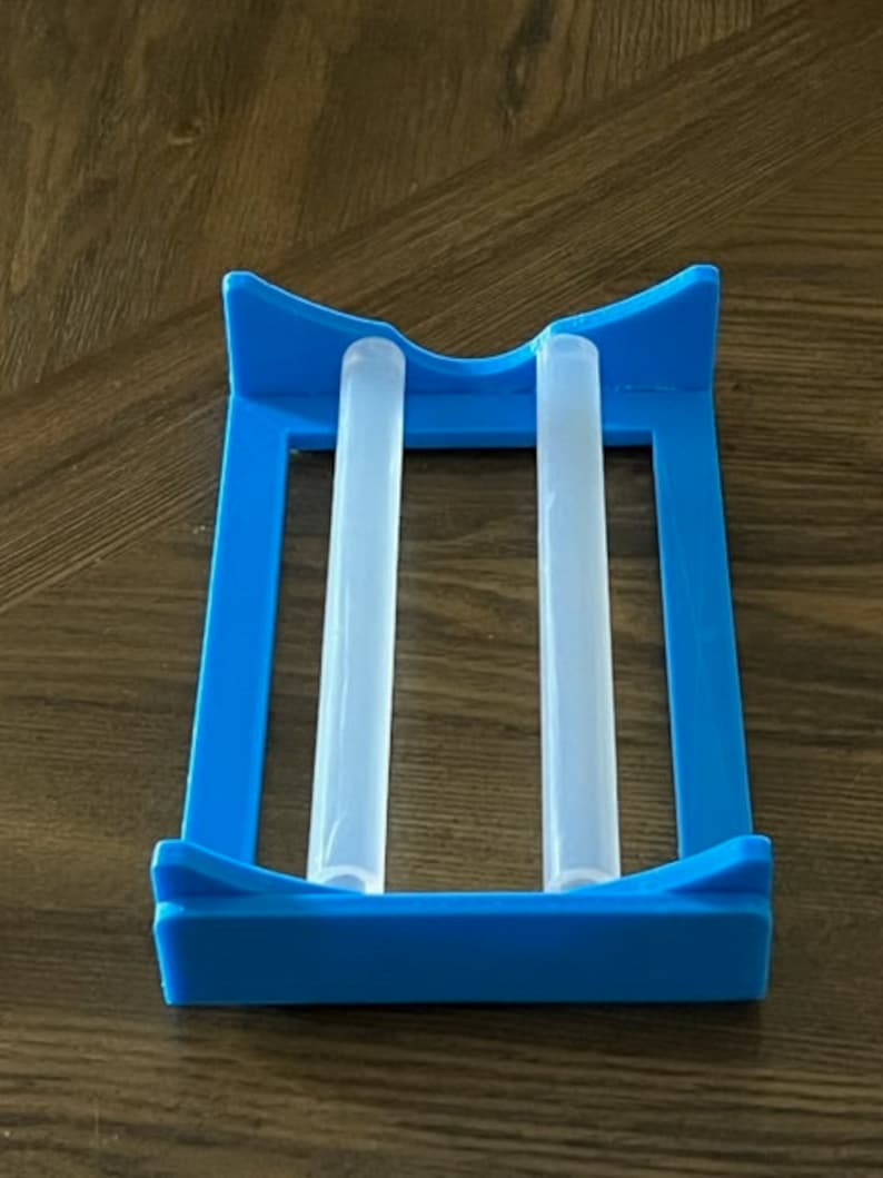 May include: A blue plastic holder with two clear plastic tubes inside. The holder is designed to hold and dry the tubes.