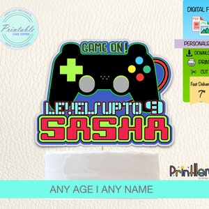 May include: A cake topper with a black game controller design and the text "GAME ON!" and "LEVELS UP TO 9 SASHA". The topper is approximately 7 inches in size and is a digital file.
