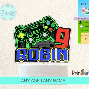 Puede incluir: Topper de pastel imprimible con un mando de videojuego verde y negro con un número 9 rojo y el nombre "ROBIN" en letras azules y amarillas. El topper mide 17,8 cm de alto.