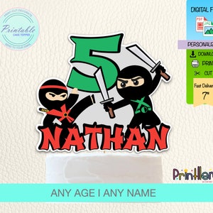 Puede incluir: Topper de pastel imprimible con un número 5 verde, dos ninjas con espadas y el nombre "NATHAN". Los ninjas llevan atuendos negros y rojos. El topper mide 17,8 cm de alto.