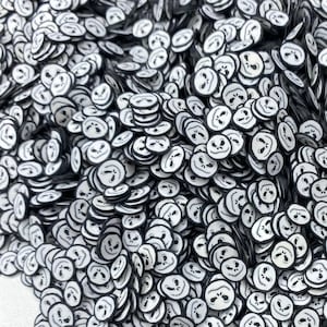 Puede incluir: Un montón grande de  sprinkles redondos blancos y negros con un diseño de cara de calabaza.