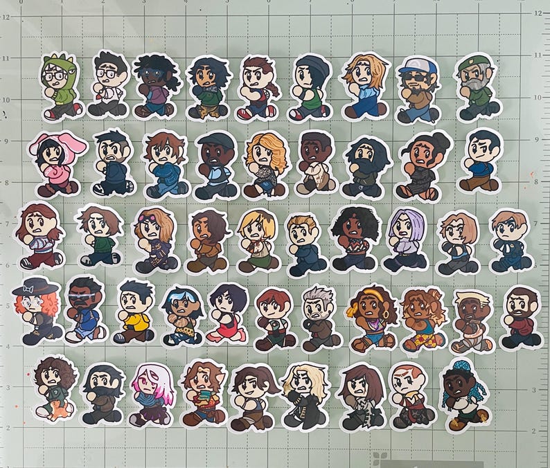 May include: A collection of fifty-two individual die-cut stickers featuring chibi-style illustrated characters in various outfits, hairstyles, and colors, arranged in five horizontal rows on a green cutting mat with a white grid pattern.