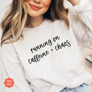 May include: A gray sweatshirt with the text "running on caffeine + chaos" in black cursive lettering.