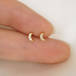 May include: A pair of gold crescent moon earrings with small clear cubic zirconia stones.
