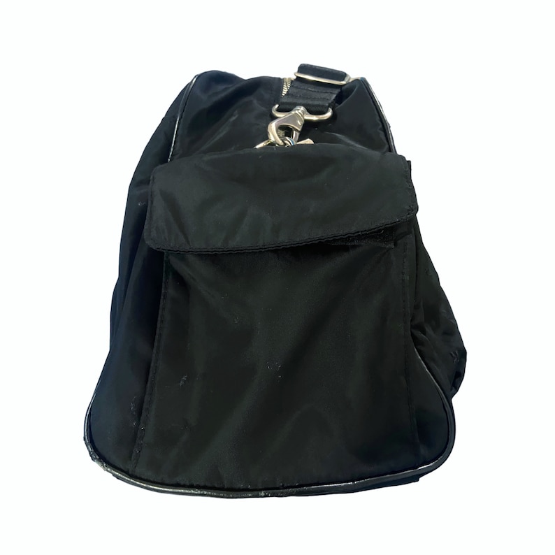 May include: Black nylon travel bag with a zippered pocket and a silver hook closure.