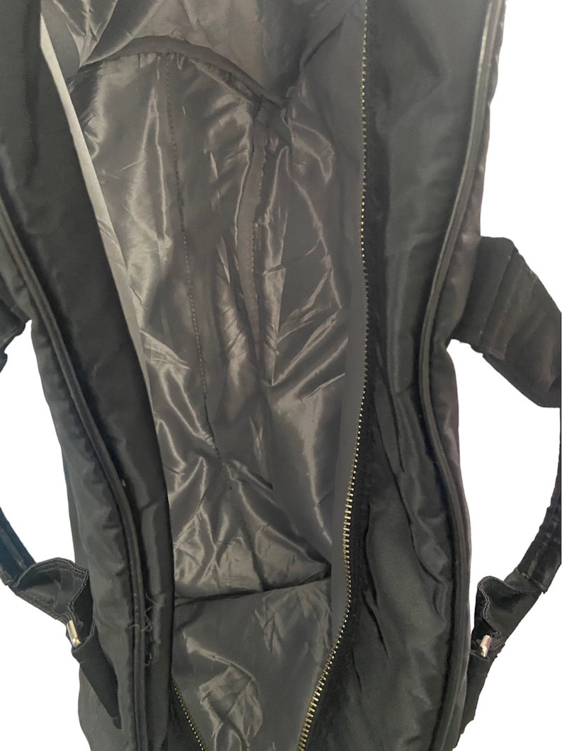 May include: Black zippered travel bag with a black lining and a zippered closure. The bag has two adjustable straps.