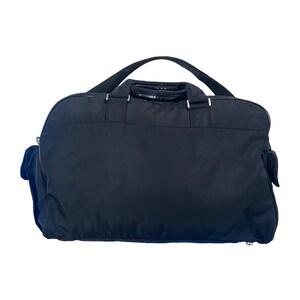 May include: A black nylon travel duffel bag with a single top handle and two side pockets.