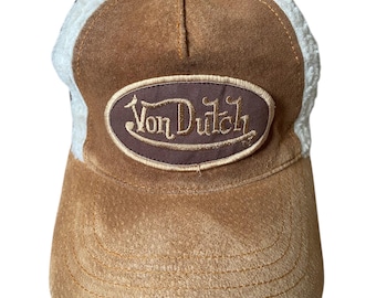 May include: A brown suede and mesh trucker hat with a brown oval patch that says "Von Dutch" in gold embroidery.