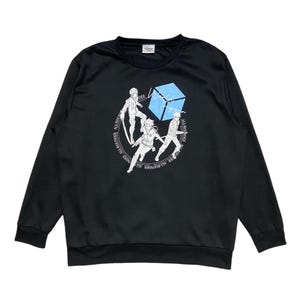May include: Black long-sleeve sweatshirt with a graphic print of four characters from the anime "Attack on Titan" standing around a blue cube. The text "All  rounder" is printed around the cube.